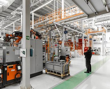 Interior de una planta industrial con maquinaria eléctrica y un técnico trabajando en la instalación